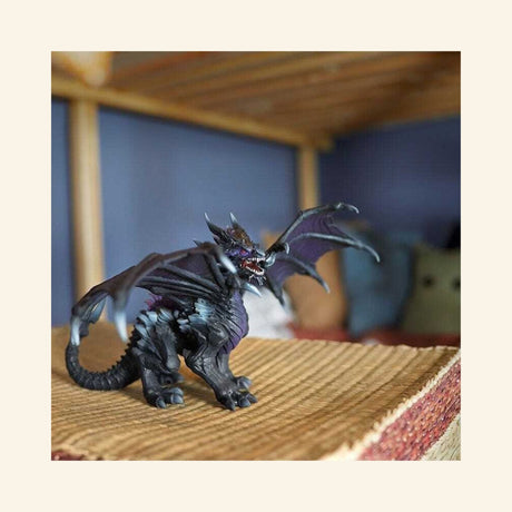 Schleich® ELDRADOR® Creatures Shadow Dragon shown in a play scene on a woven surface with wings extended and dark fantasy creature detailing.