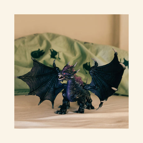 Schleich® ELDRADOR® Creatures Shadow Dragon shown in a bedroom play scene with wings spread in front of green bedding.