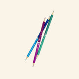 Three Snifty double-ended metallic colored pencils in teal, blue, and purple shown diagonally, highlighting sharpened tips on both ends.