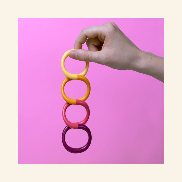 Hand holding the SPEKS 8 Helix Purple Plasma magnetic fidget coil vertically to demonstrate its flexible magnetic design.