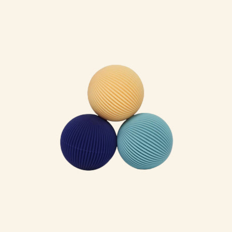 Three Speks Odds Lines magnetic fidgets in cream, navy blue, and teal, featuring rounded shapes covered in fine ridged lines.