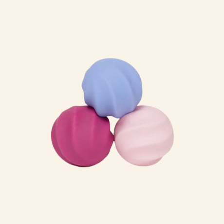 Three Speks Odds Swirls magnetic fidgets in periwinkle blue, magenta, and pale pink, featuring smooth rounded forms with curved spiral grooves.