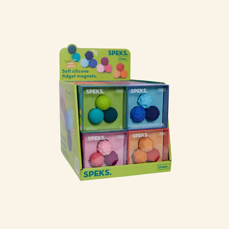 Retail display of Speks Odds soft silicone fidget magnets, showing multiple three-piece sets in assorted colors and textured shapes including Lines, Puffs, Spurs, and Swirls.