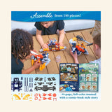 Children assembling the Thames & Kosmos Mega Cyborg Hydro Blaster at a table with the instruction manual, plastic parts, and completed orange-and-blue blaster pieces spread out in front of them.