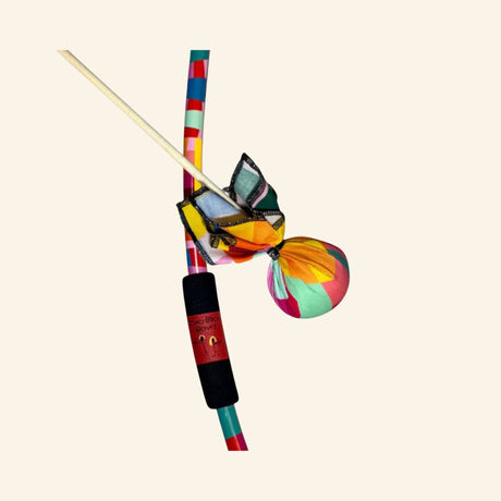 Two Bros Bows Mosaic bow and arrow set featuring a colorful striped bow with a black grip, two arrows with multicolored soft ball tips, and bright fabric accents.